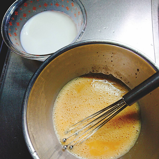 温めた牛乳を解きほぐした卵液に入れてプリンのタネをつくる
